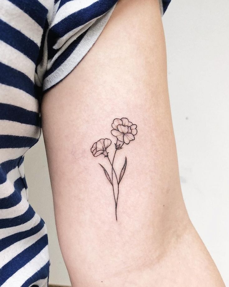 a small flower tattoo on the right arm and shoulder, it looks like flowers are growing out of the ground