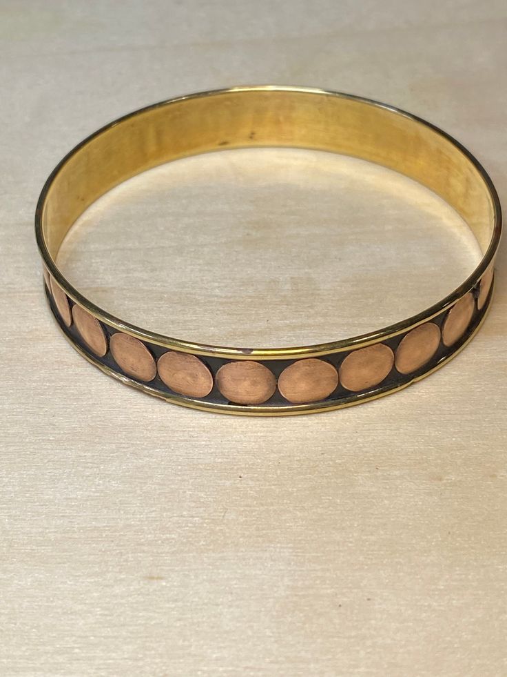 Beautiful brass and copper bangle.  The copper spots attached to brass bangle with a black type of lacquare. The bangle is stunning and light and definitely a statement piece. Measurements:  internal diameter is 6.8cm, external diameter is 7cm and bangle is 1.2cm. Condition:  Excellent vintage condition.  No scratches, dents, or imperfections.  Some patina on the inside of the bangle Hallmark:  None The pieces available are preloved and are ready for their new home.  Due to this they may have minor imperfections and unique characteristics.  Be assured these pieces are of great quality and offer great history to the wearer.  Sustainability, reclaiming and keeping valuable treasures out of landfill is Grandma's Rings aim.   I clean all jewellery with mild soap and warm water when I receive t Stackable Bangles, Brass Bangle, Brass And Copper, Fake Tan, Me Clean, Wire Earrings, Boho Hippie, Vintage Brass, Hippie Boho