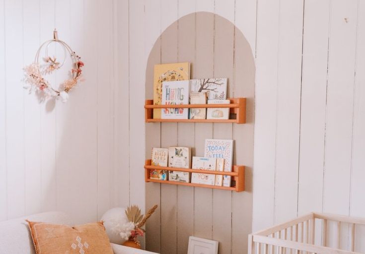 a baby's room with white walls and wooden shelves on the wall next to a crib