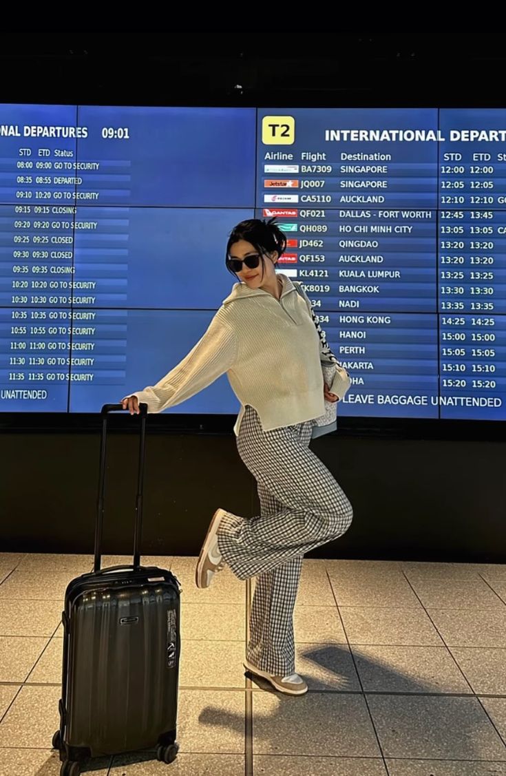 a woman is standing with her luggage at the airport