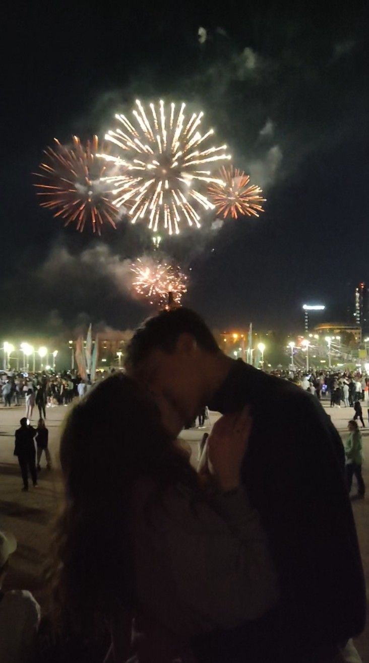 a man and woman kissing in front of fireworks