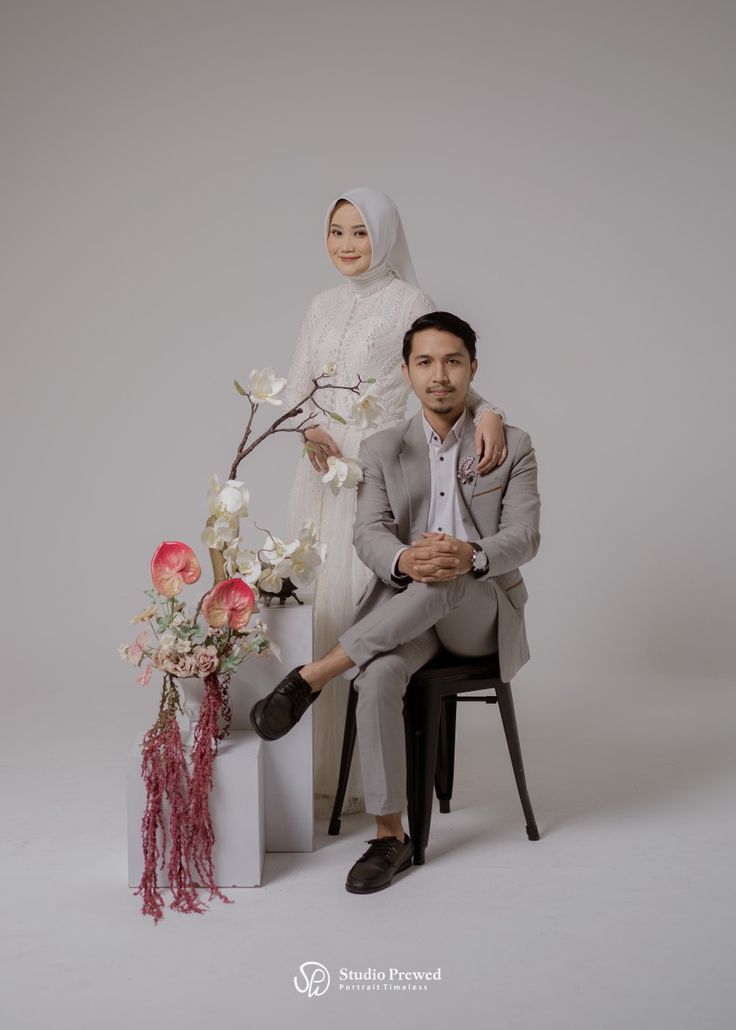 a man and woman sitting next to each other in front of a vase with flowers