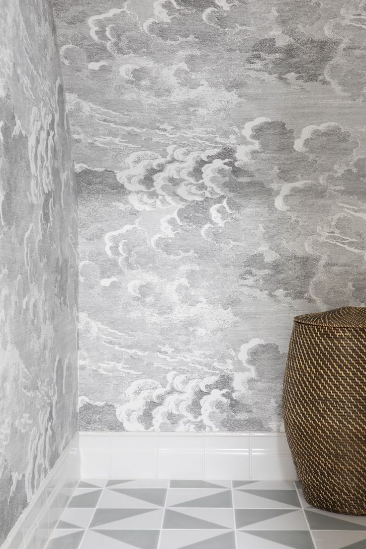 a basket sitting on the floor in front of a wall with clouds painted on it