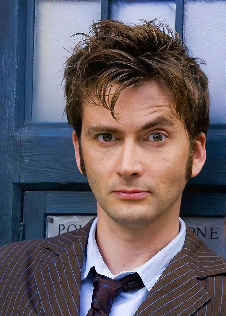 a man wearing a suit and tie standing in front of a blue door with the doctor's name on it