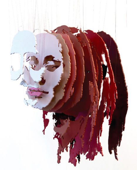 a woman's face is made out of strips of red, white and brown paper