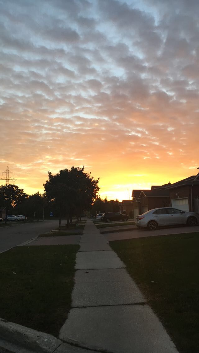 the sun is setting over some houses and cars