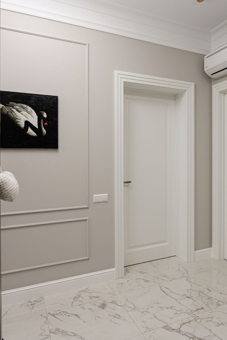 an empty room with marble flooring and white trim on the walls, along with two doors leading to another room