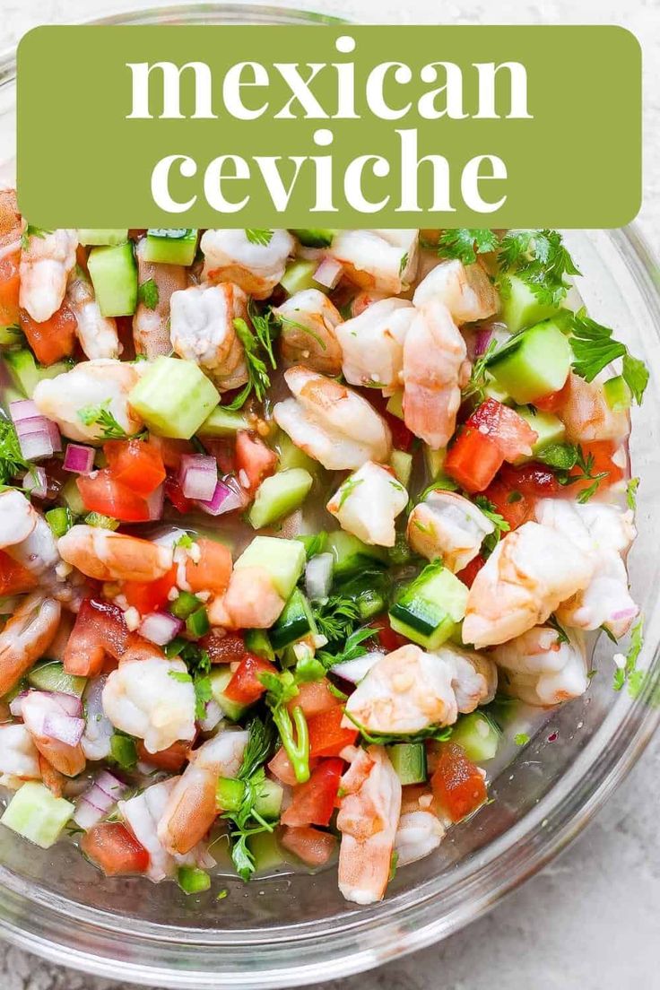 a glass bowl filled with shrimp, cucumber and tomato salad on top of a white table