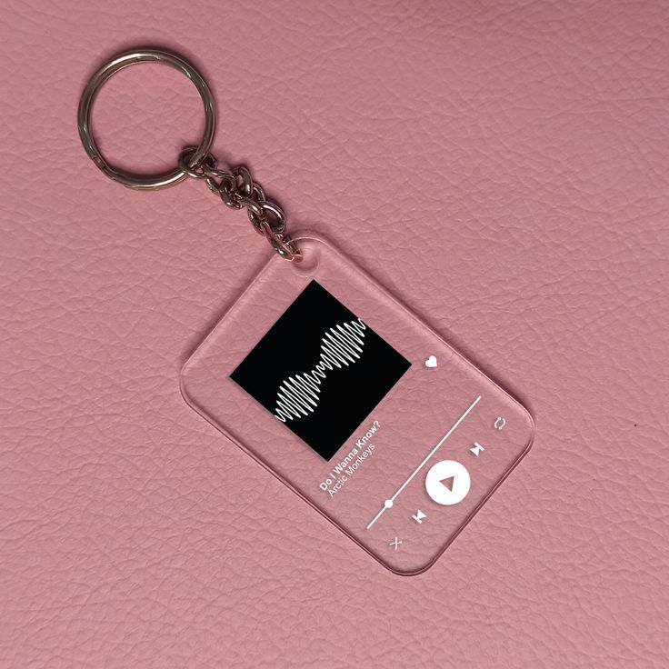 an mp3 player keychain on a pink leather surface