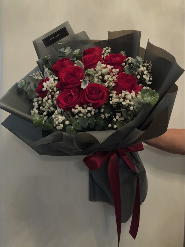 a bouquet of red roses wrapped in gray paper