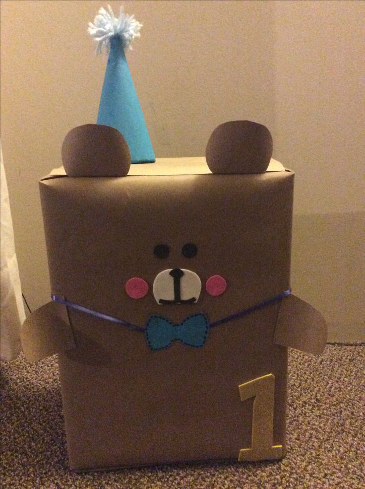 a cardboard box with a teddy bear on it and a blue party hat on top