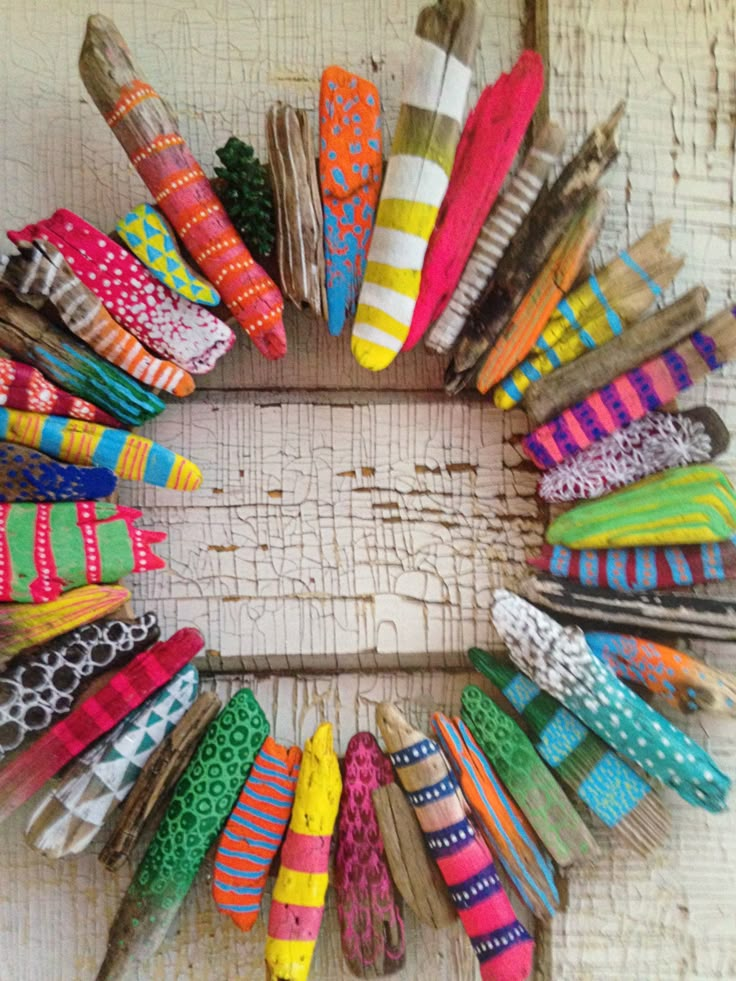 a wreath made out of old clothes pegs and colorful fabric ties on a white wooden background