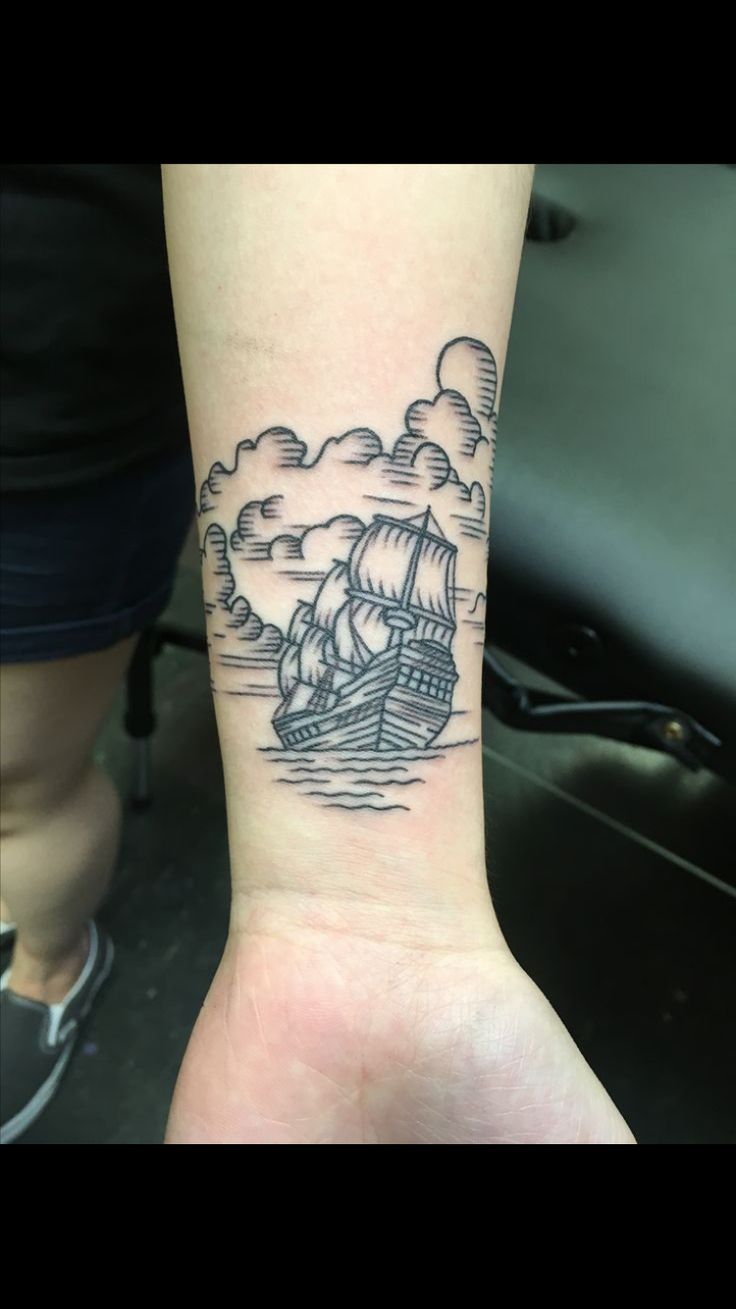 a black and white photo of a ship on the wrist with clouds in the sky