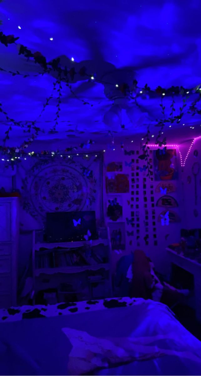 a bedroom with purple lighting and decorations on the ceiling