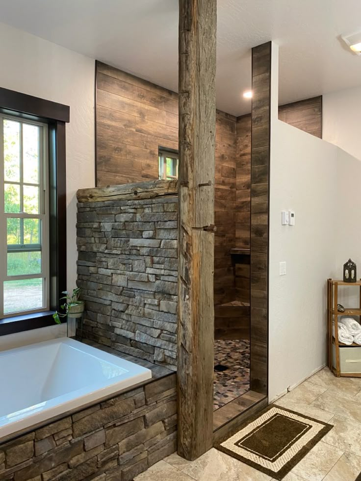 a large bathroom with stone walls and flooring next to a bathtub in front of a window