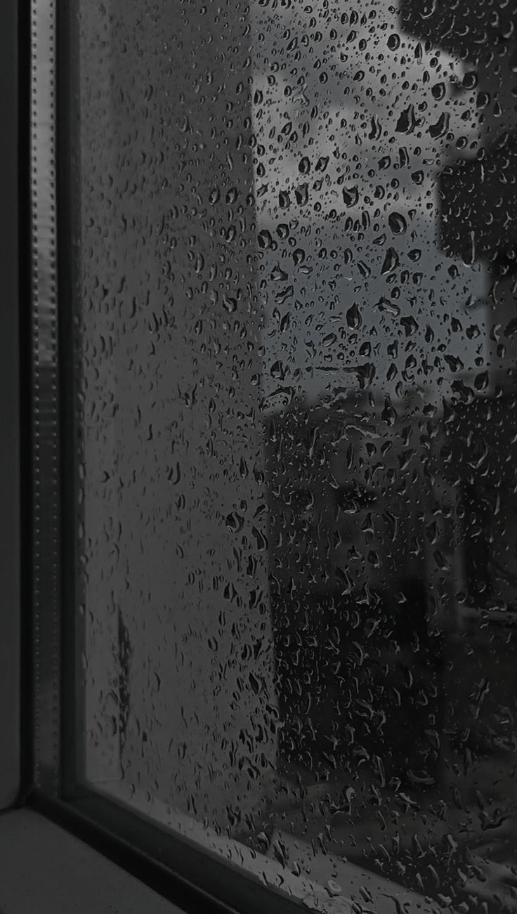 rain drops on the window pane as it is raining in front of a building