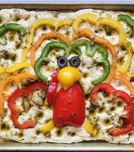 a pizza with peppers, cheese and chicken on it is decorated like a bird's head