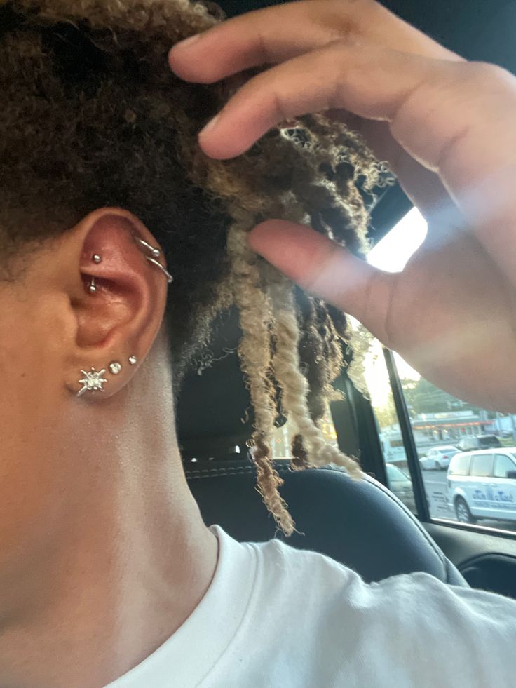 a person with dreadlocks in the back seat of a car holding their hand up to her ear