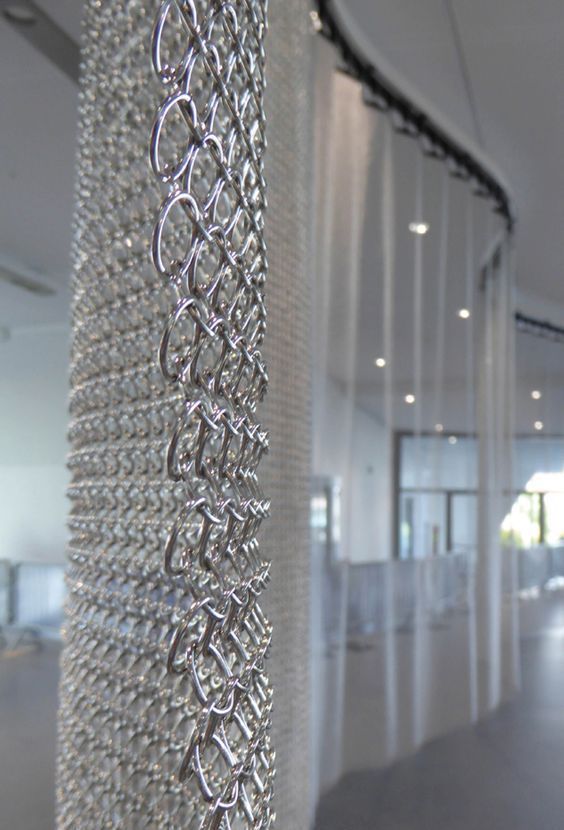 the inside of an office building with white walls and metal chains hanging from the ceiling