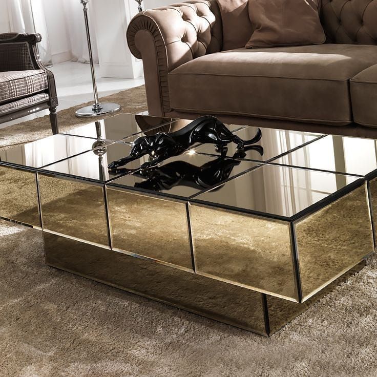 a glass coffee table sitting on top of a carpeted floor next to a couch