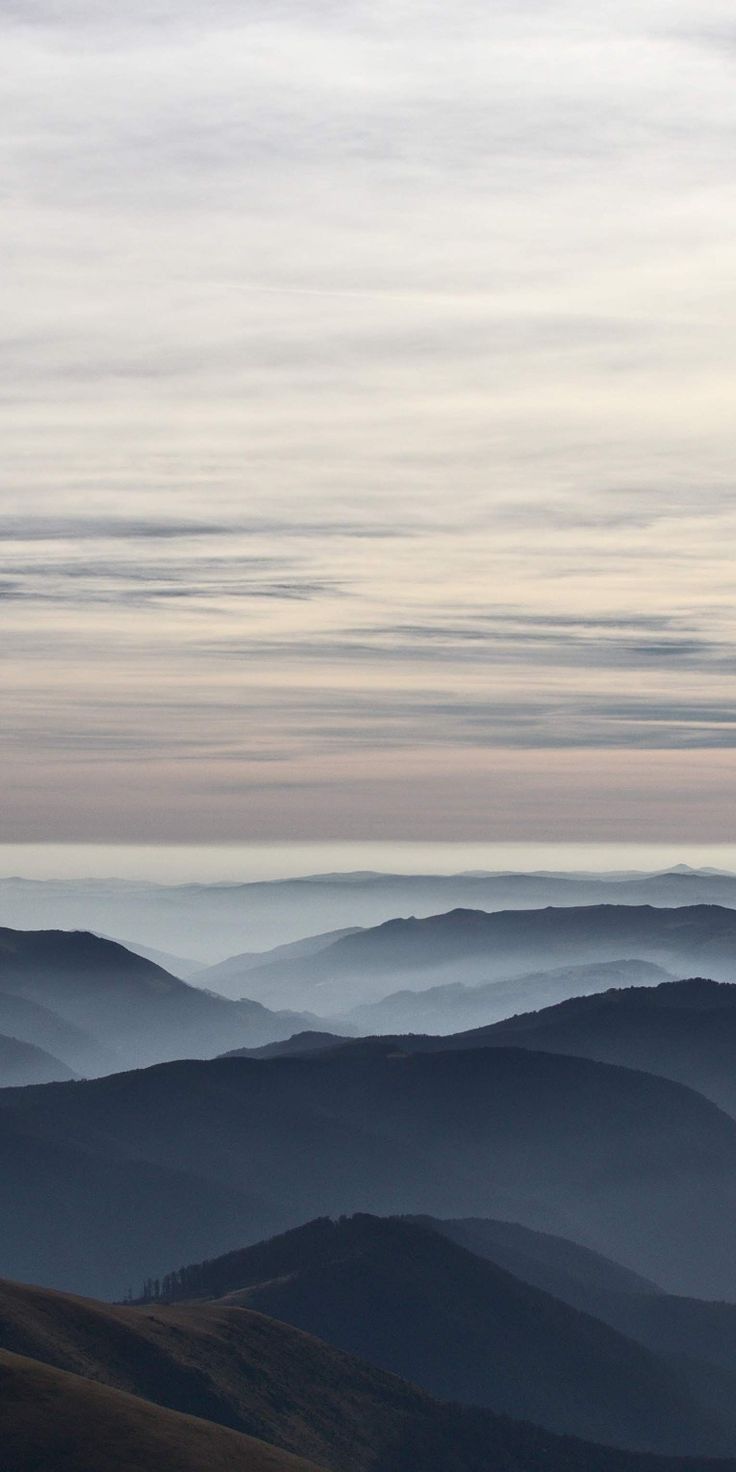 the mountains are covered in fog and haze as seen from an overlook point on a cloudy day