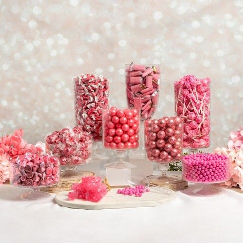 there are many pink and white candies in the glass vases on the table