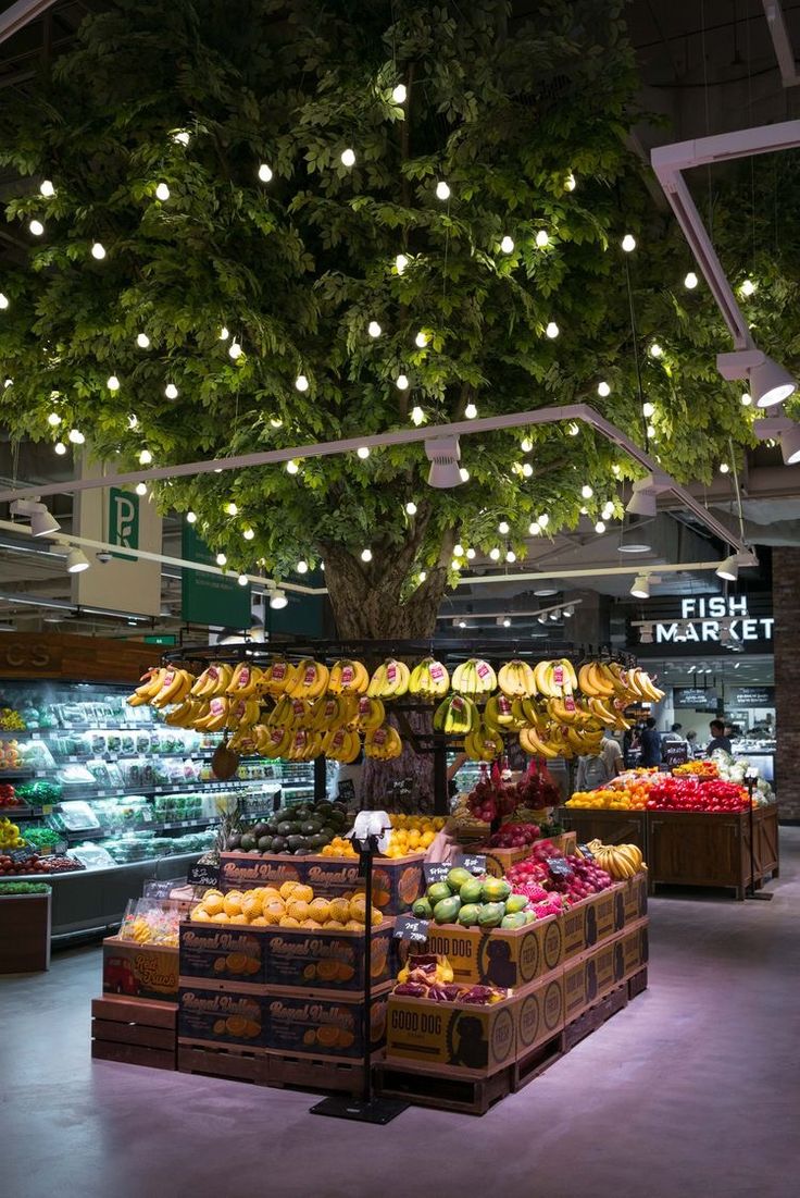 an open market with lots of fruits and vegetables on display under the lights hanging from the ceiling