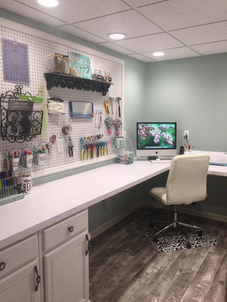 a desk with a computer on it and lots of crafting supplies hanging from the wall