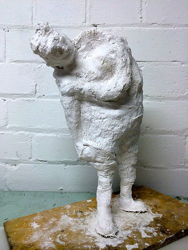 a white sculpture of a dog standing on top of a wooden table next to a brick wall