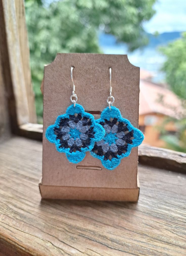 a pair of blue and black crocheted flower earrings