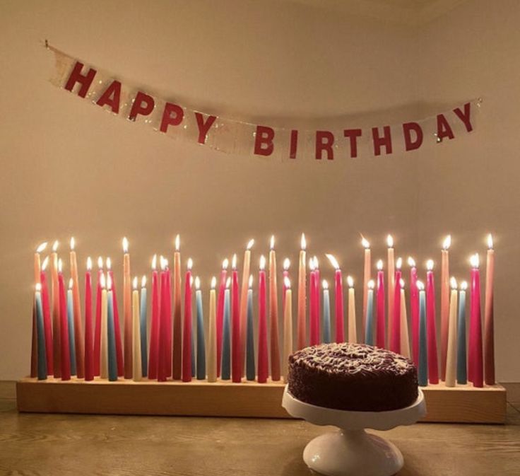 a birthday cake sitting in front of a row of lit candles with the words happy birthday on it