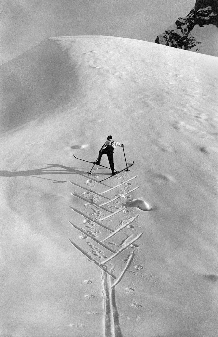 a man riding skis on top of a snow covered slope in the middle of winter