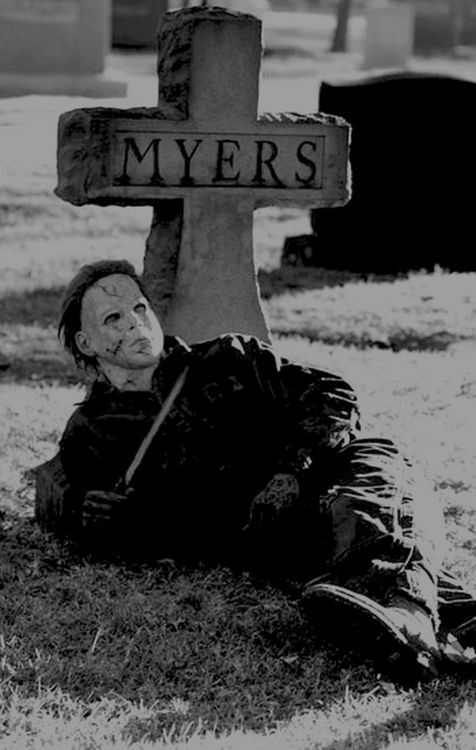 a person laying on the ground in front of a grave with a cross behind them