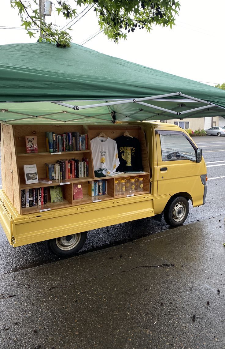 a yellow truck parked under a green awning on the side of a road next to a street