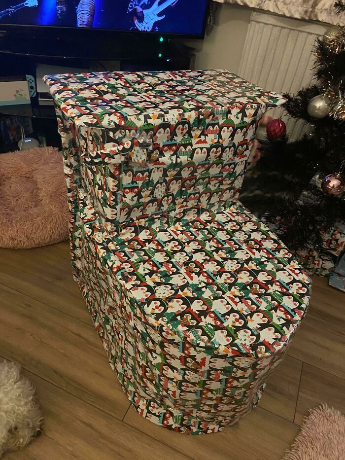 a large stack of wrapped presents in front of a christmas tree on the floor next to a tv