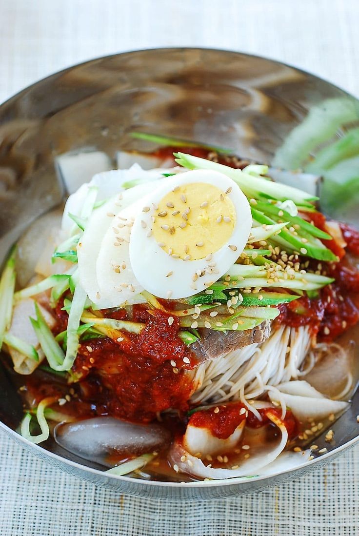 a bowl filled with noodles, meat and an egg on top of it's side