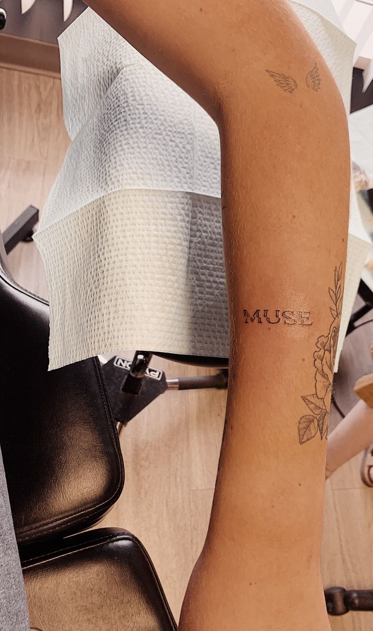 a woman with a tattoo on her arm sitting in a chair next to a bag