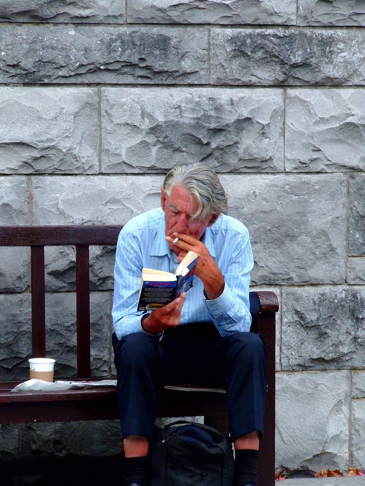 a man sitting on a bench reading a book