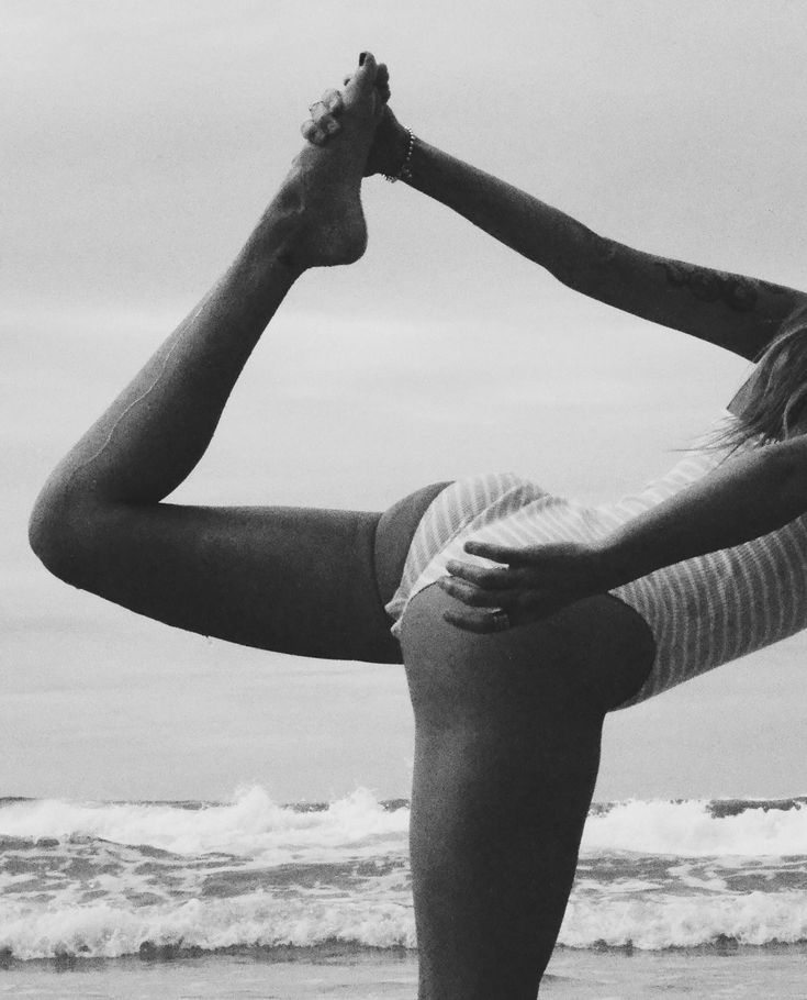 a woman doing yoga on the beach in front of the ocean