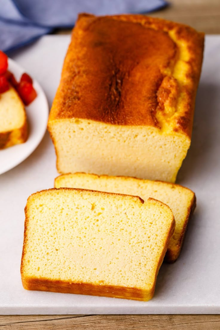 slices of pound cake sitting on top of a cutting board with strawberries in the background