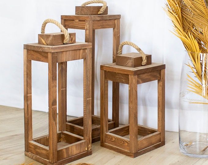 three wooden tables sitting on top of a hard wood floor next to a glass vase