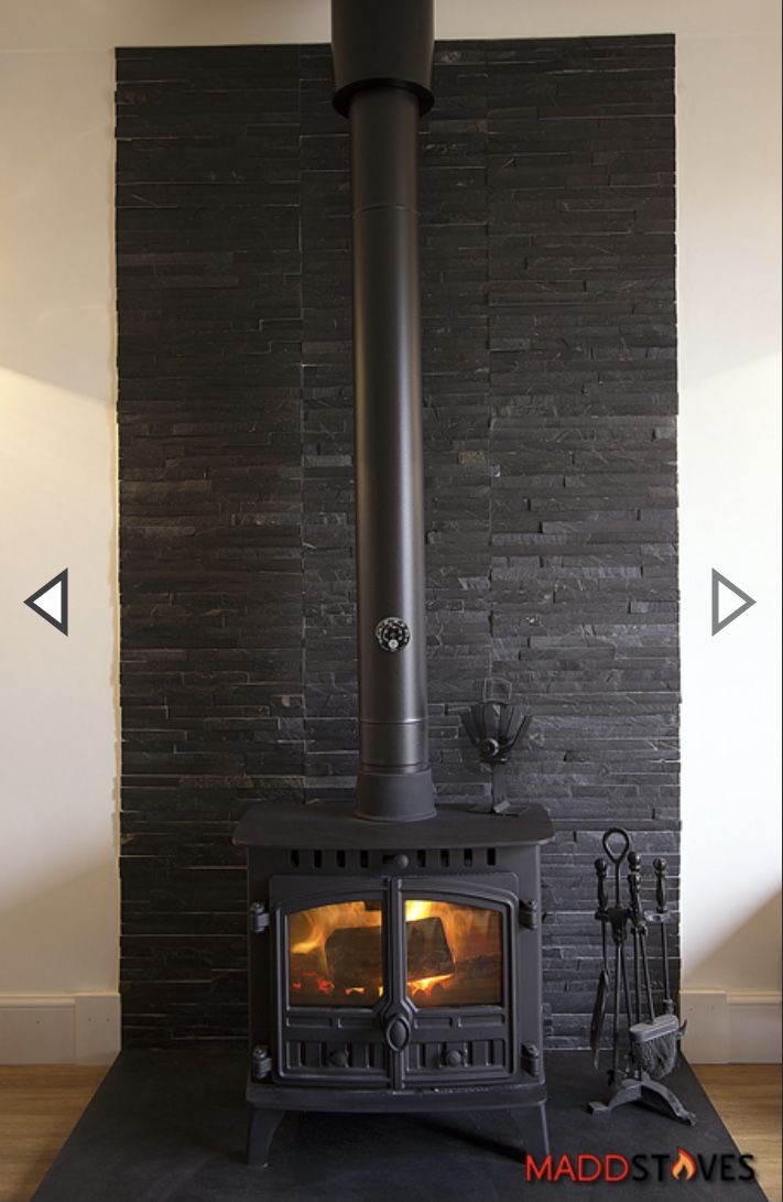 a fireplace with a black brick wall and wood burning in it