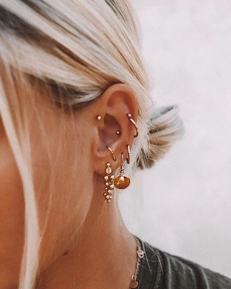 a close up of a person wearing ear rings and earrings with an orange circle in the background