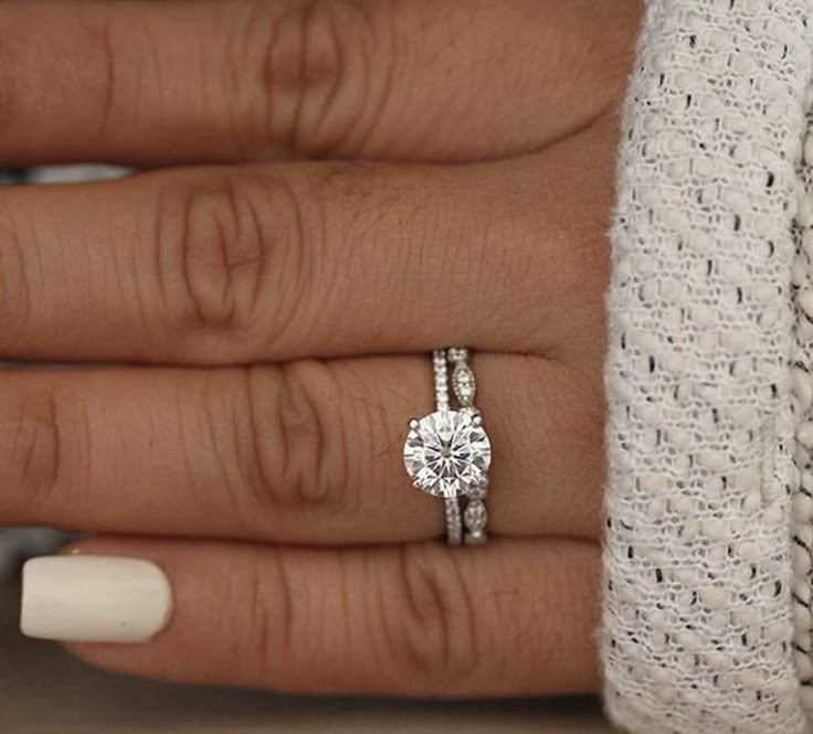 a woman's hand with two engagement rings on top of her finger and the other ring