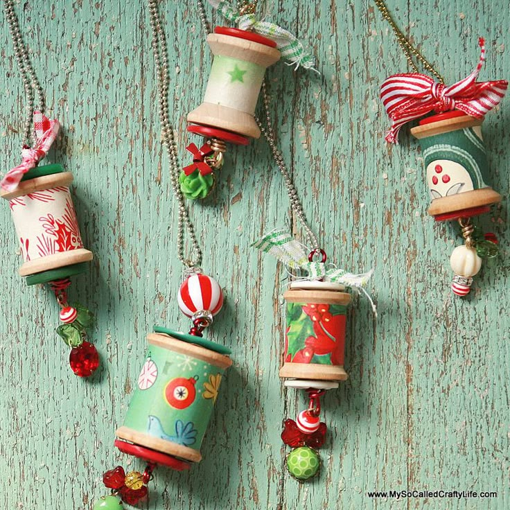 christmas ornaments are hanging on a green wooden surface with beads and bells attached to them