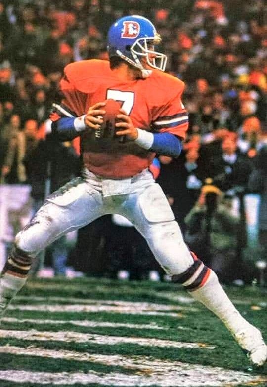 a football player in an orange and white uniform holding a ball while standing on the field