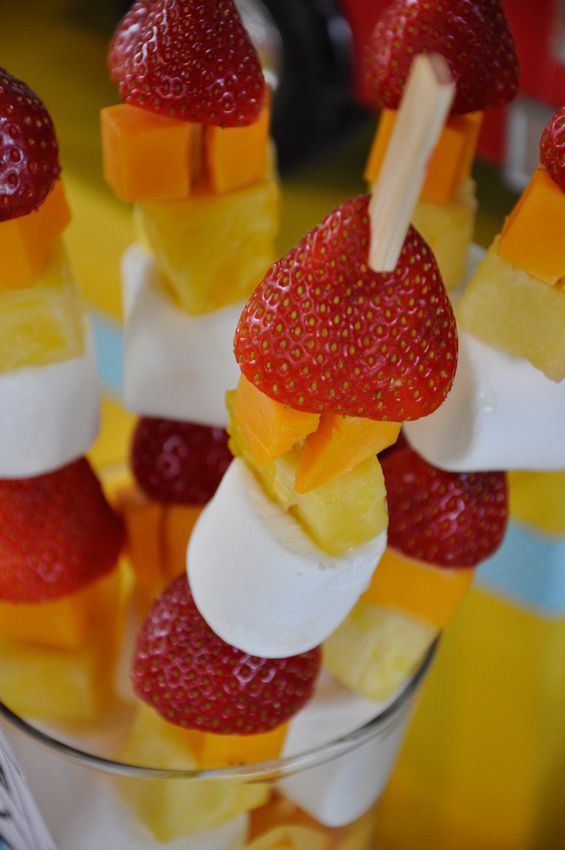 strawberries, pineapples and marshmallows are arranged on skewers