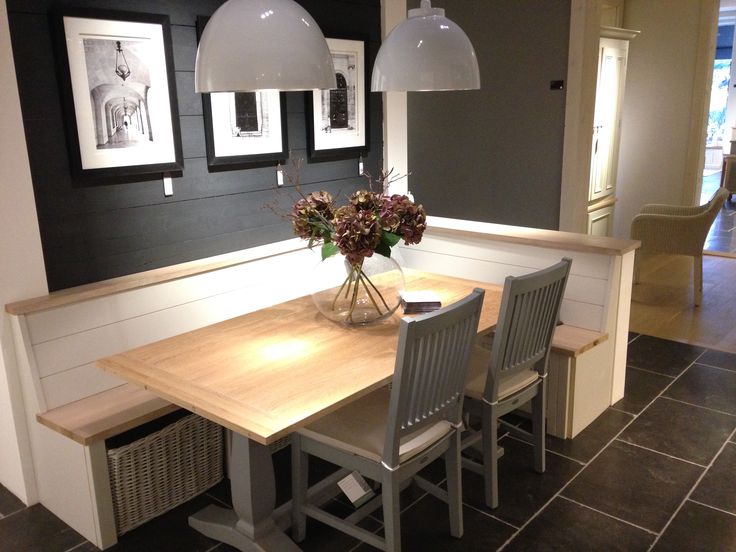 a dining room table with chairs and pictures on the wall behind it, along with two pendant lights