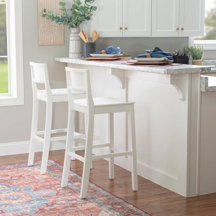 two white stools sit at the center of a kitchen island