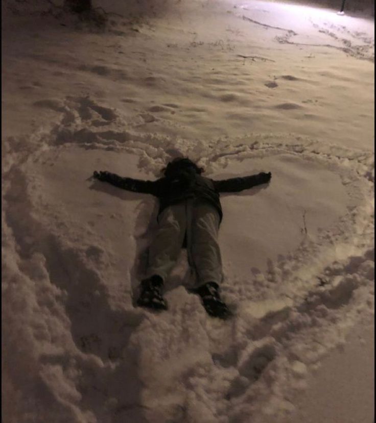 a person laying in the snow with their arms spread out to form a heart shape